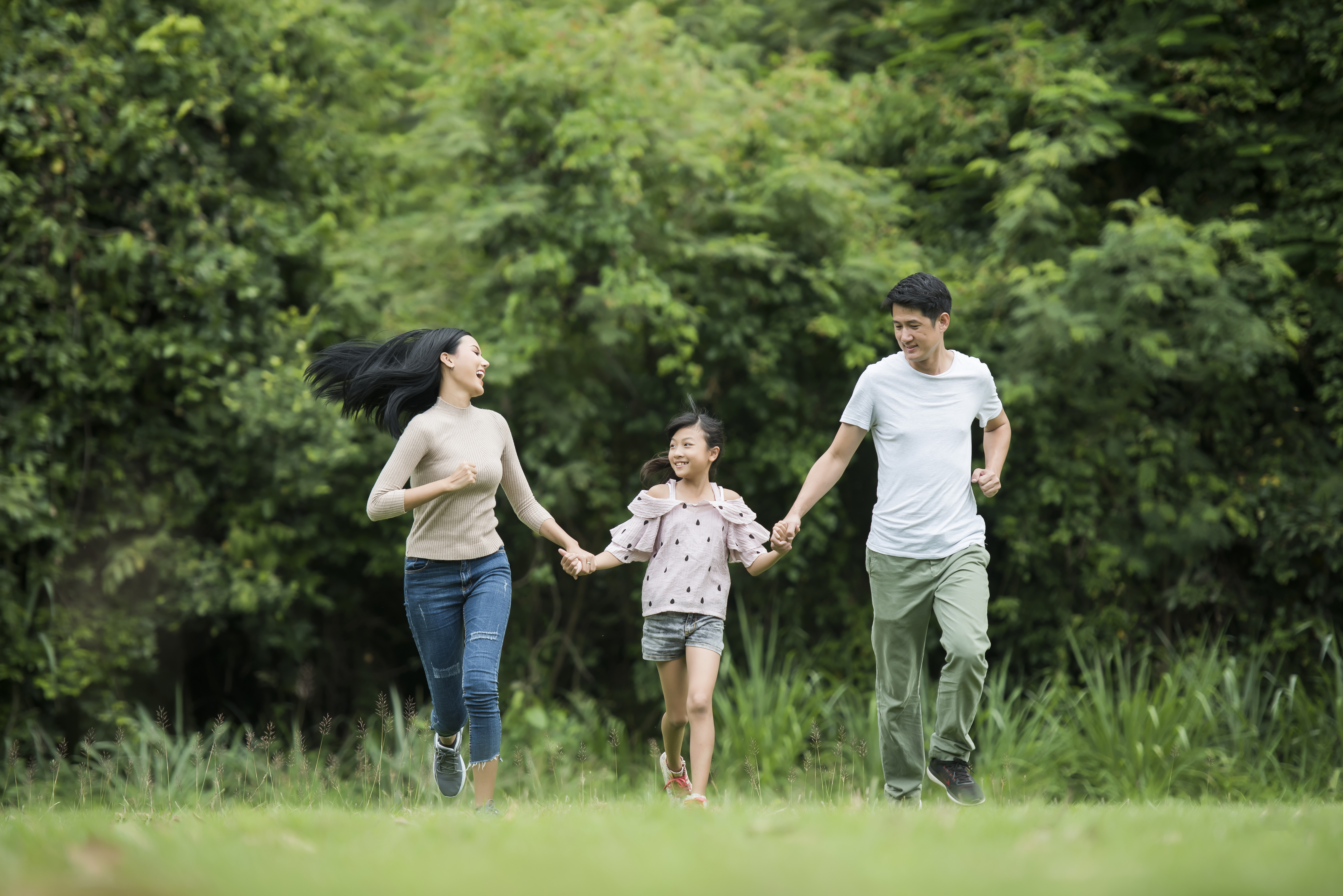 Parents and daughter running together in a park