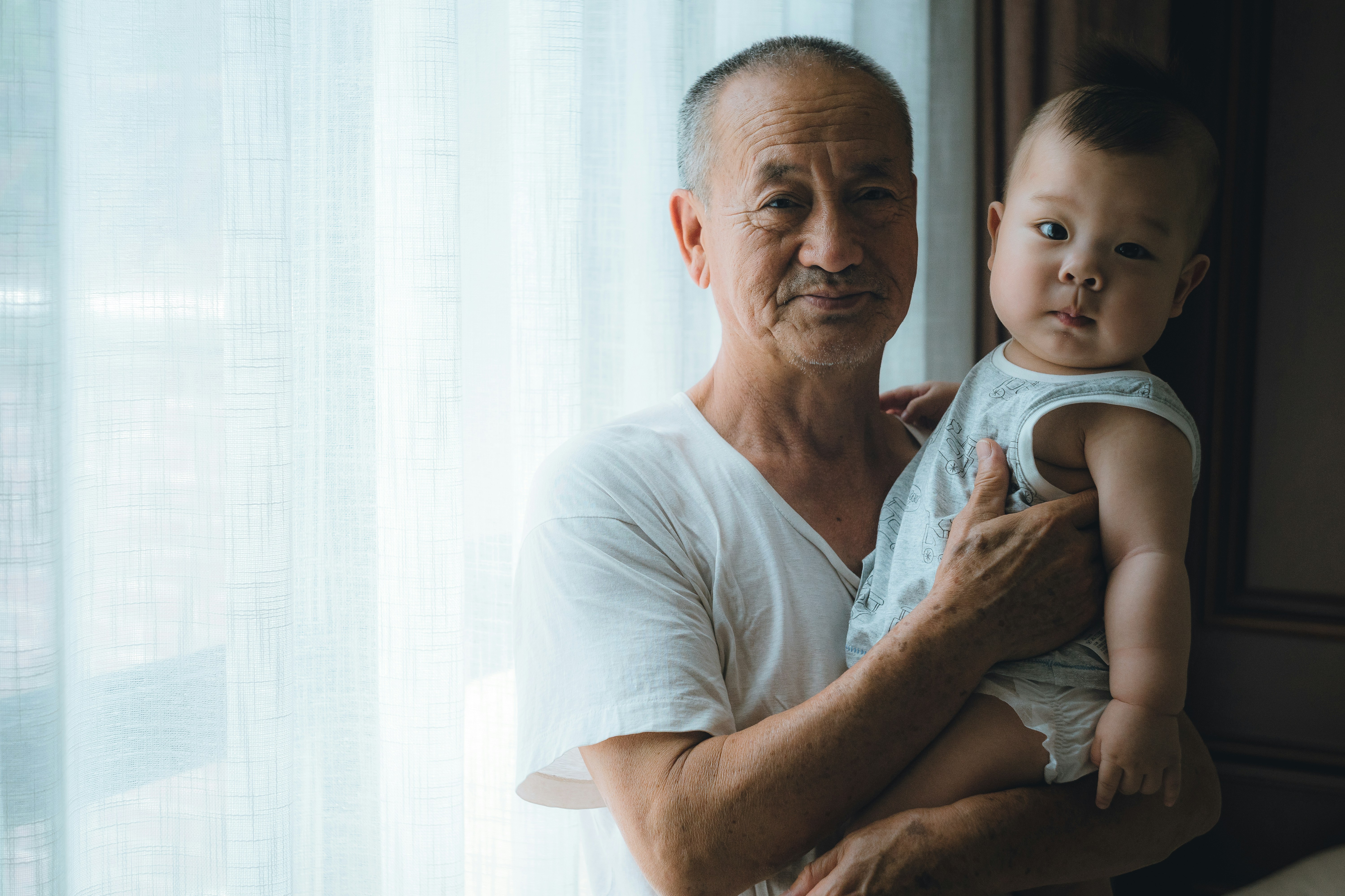 Grandfather holding a baby in soft window light